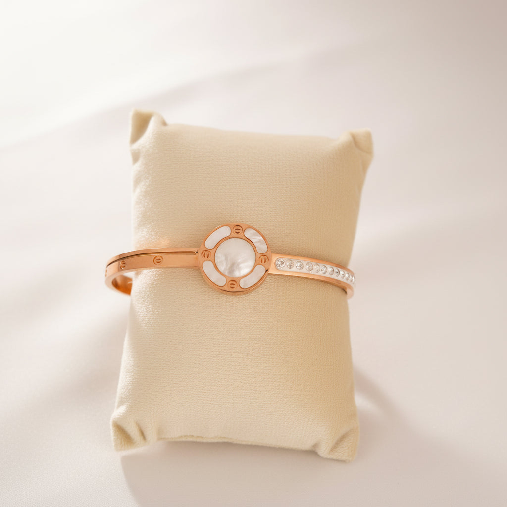 Rose gold bracelet with a central stone on a yellow pillow with flowers in the background